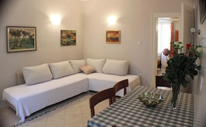 Ein Zimmer mit einer Couch, einem Tisch mit kariertem Tischläufer und einer Vase mit Blumen.