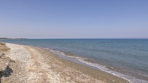 A beach with pebbles and sand, calm water, and a clear sky. - Larnaca Chelidonia Seafront Villa (Pervolia)
