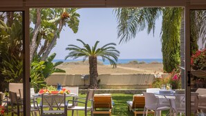 An outdoor patio with a table and chairs, a palm tree, and a view of the beach. - Larnaca Chelidonia Seafront Villa (Pervolia)