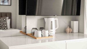 Una cocina moderna con encimera blanca, cafetera y una bandeja con tazas.