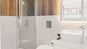 Een moderne badkamer met een glazen douchecabine, een witte wastafel en een toilet.