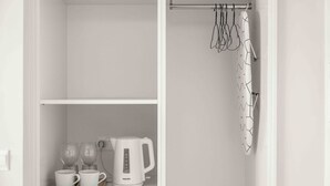 A white closet with a shelf containing a coffee maker, cups, and glasses. - Coastal Seaside Residences 04 (Limassol)