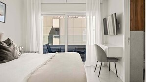 A modern hotel room with a large bed, a desk, and a TV. - Coastal Seaside Residences 04 (Limassol)