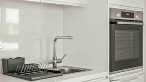 Eine moderne Küche mit weißen Schränken, einer Edelstahl-Spüle und einem Backofen.