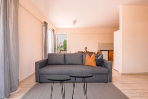 Relax in this stylish living room with a sofa, two side tables, and a large window.