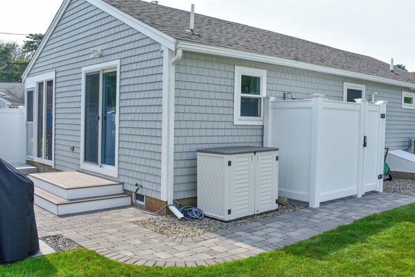 A residential building with a covered patio, a small shed, and a utility box.