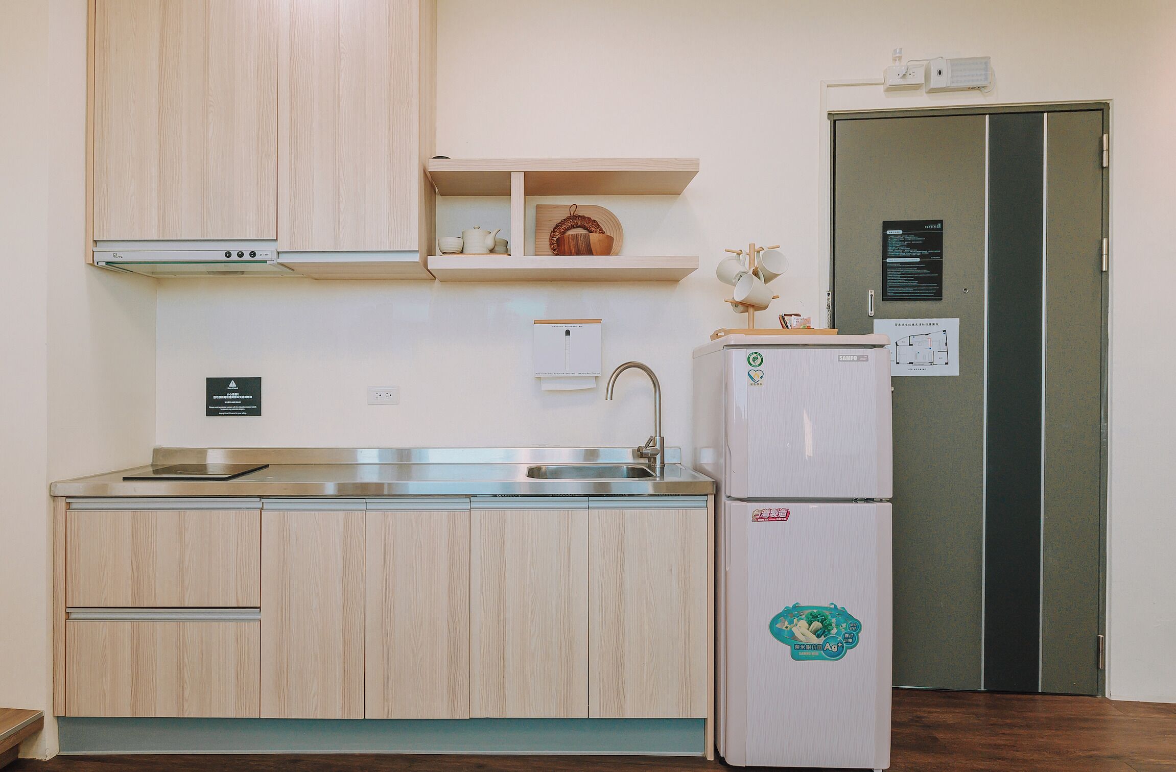 Una cucina con mobili in legno, un lavello in acciaio inossidabile, un frigorifero e un forno a microonde.