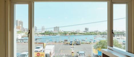 A view from a window overlooking a parking lot with a marina and city buildings in the background.