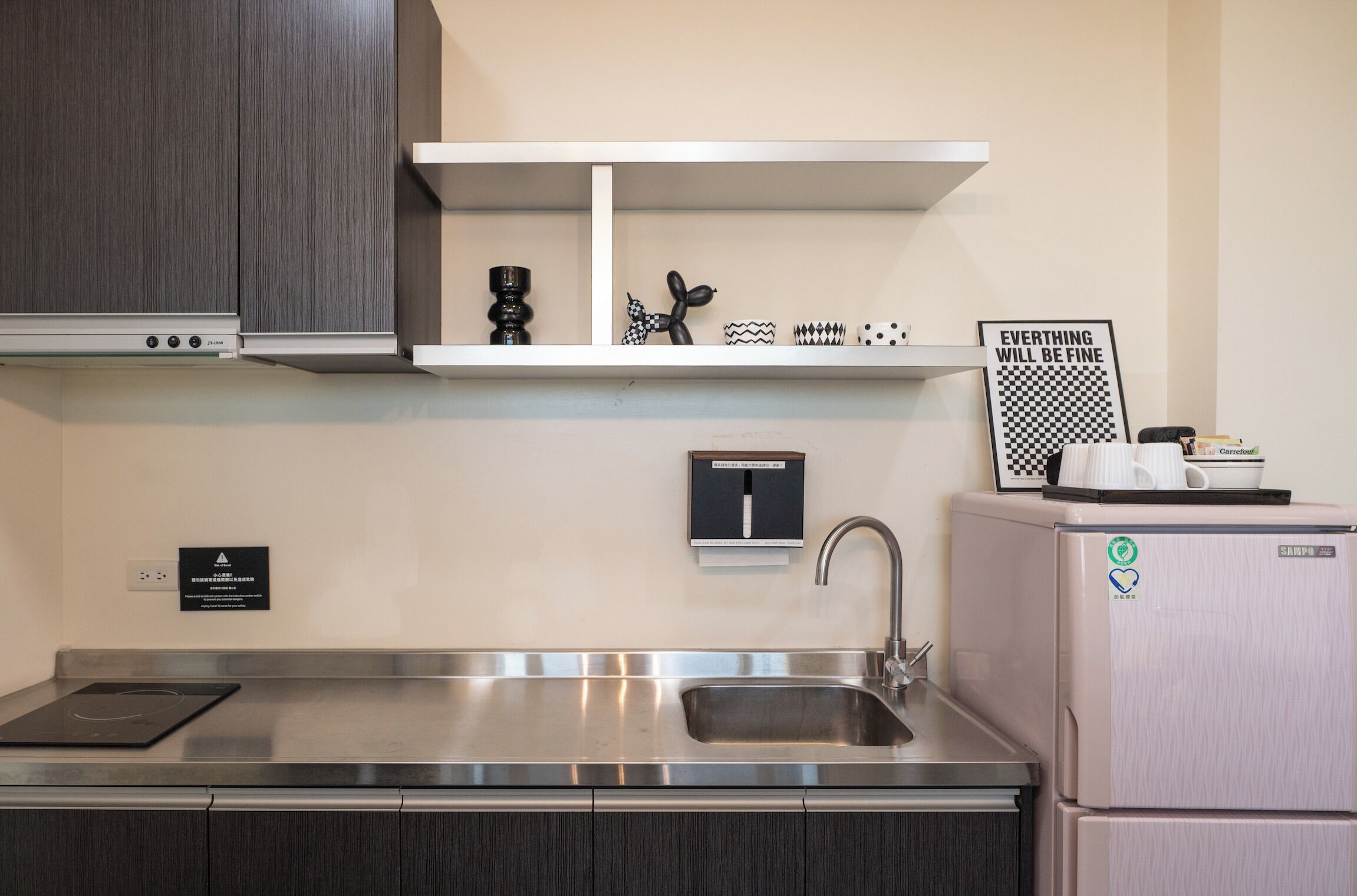 A modern kitchen with a stainless steel countertop, a built-in sink, and a refrigerator.