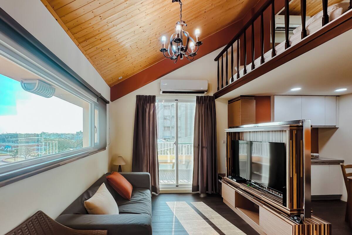 A modern living room with a sofa, TV, and wooden ceiling.