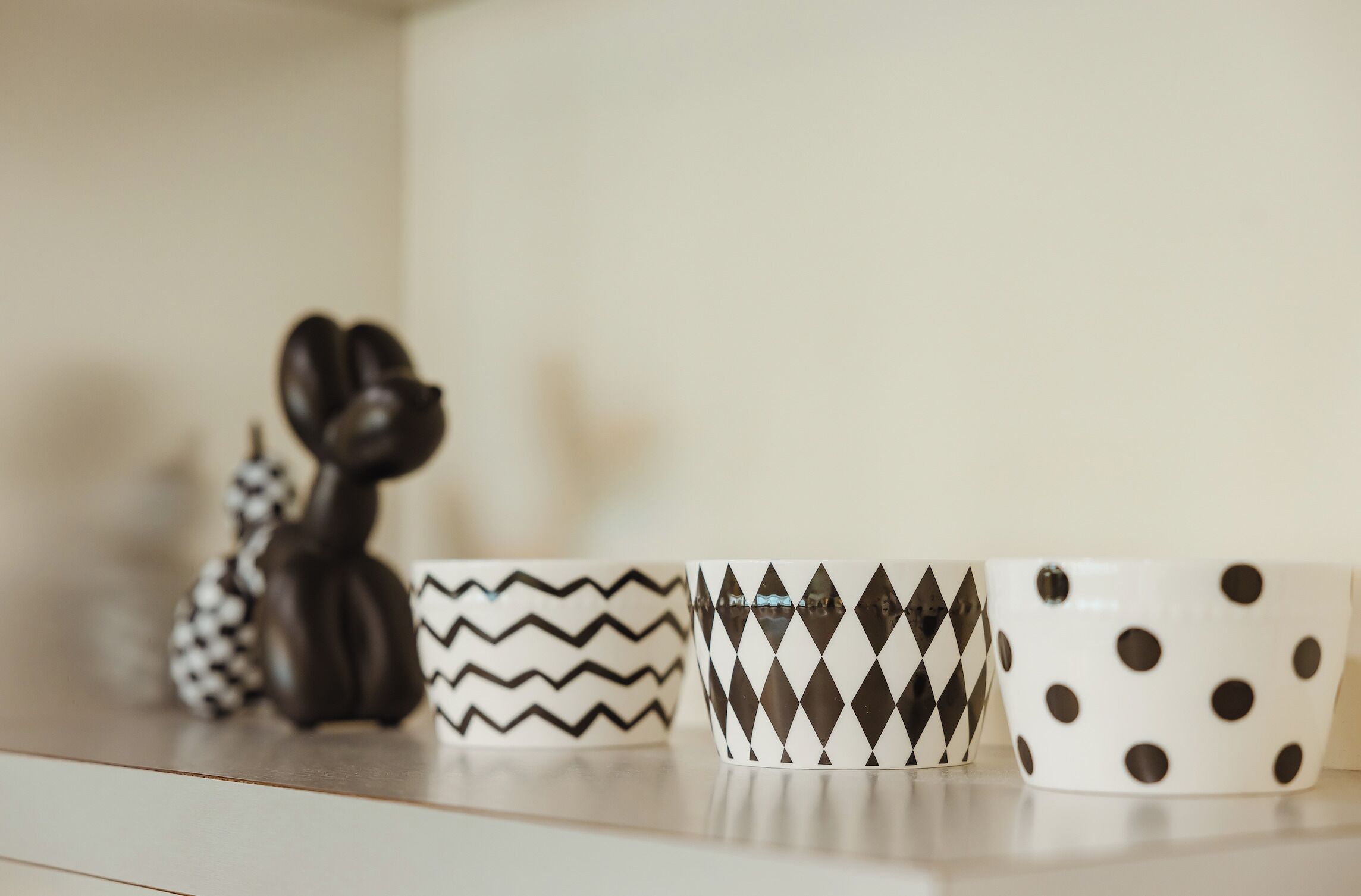 Trois tasses en céramique aux motifs différents, posées sur une étagère.