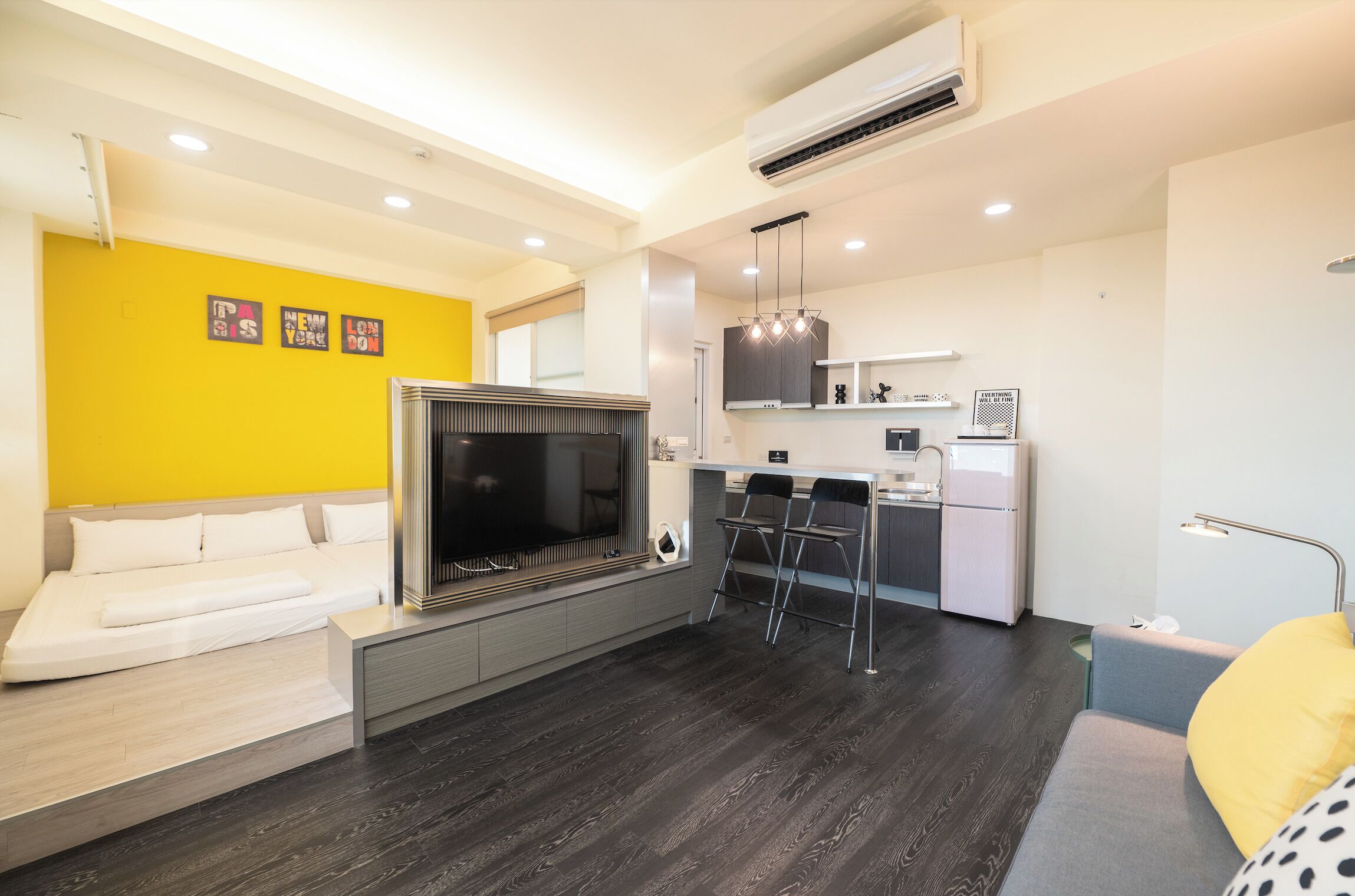 A modern living room with a sofa, a TV, and a kitchen area with a bar counter.