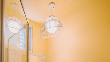 Une salle de bain avec un lavabo blanc, une cabine de douche en verre et un mur jaune.