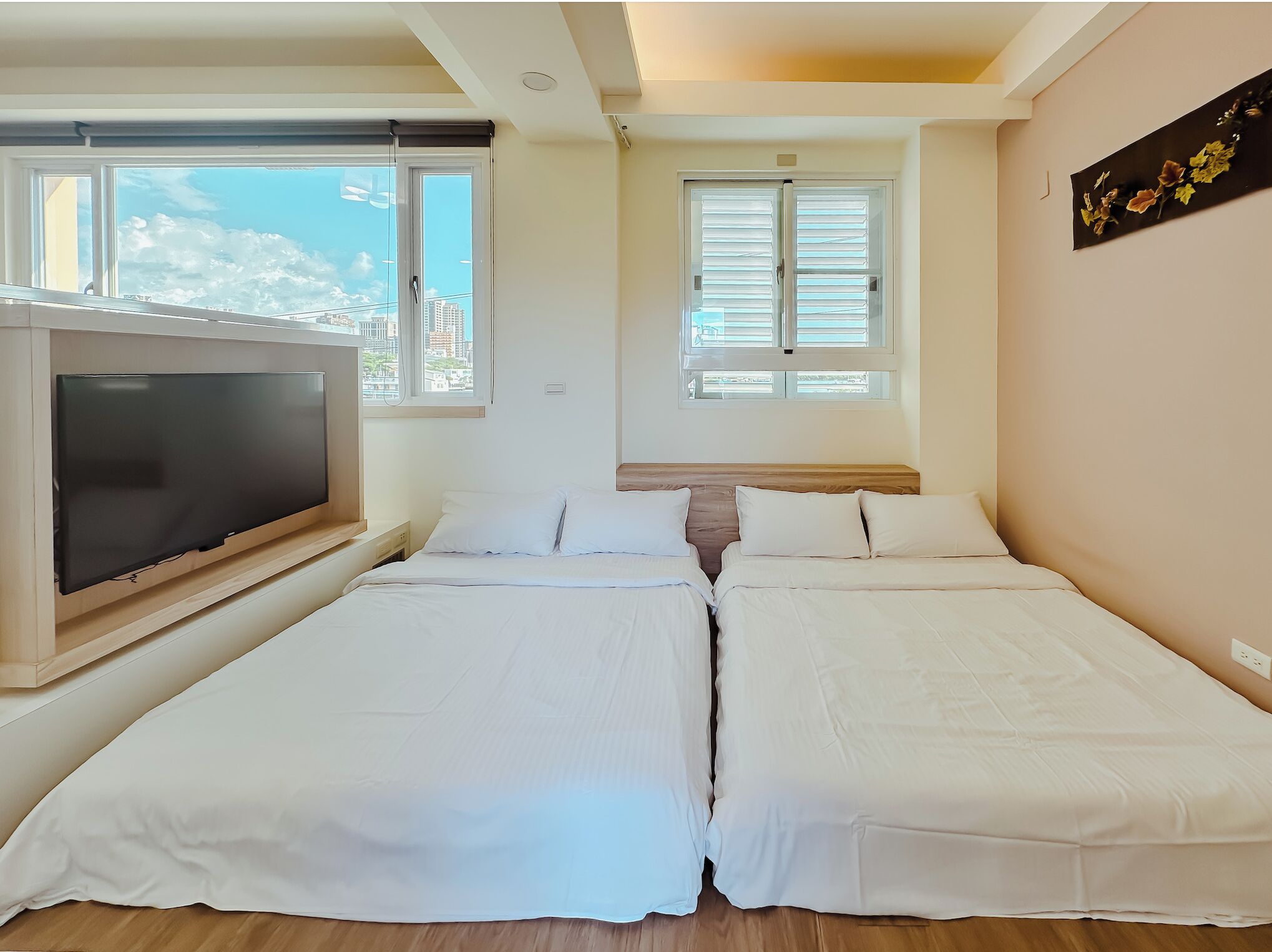 Ein Schlafzimmer mit zwei Betten, einem Fernseher und einem Fenster mit Jalousien.