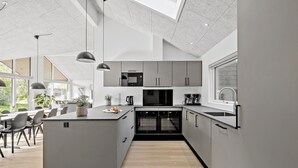 A modern kitchen with a central island, built-in appliances, and pendant lighting.