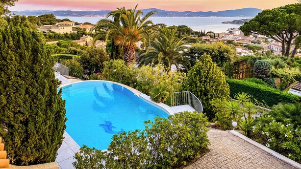 A pool surrounded by lush greenery and a view of a coastal town. - Exklusives Ferienhaus mit Traumhaftem Meerblick in Sainte Maxime (Sainte-Maxime)