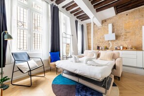 A modern bedroom with a bed, a chair, a desk, and a stone wall. - Typical Parisian Apart#Quatier Latin#Notre Dame# (Paris)