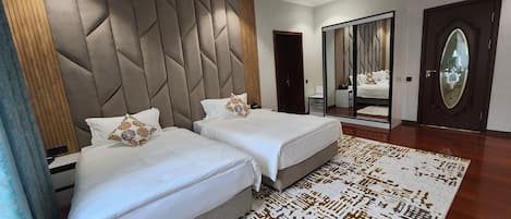 A modern hotel room with two beds, a large mirror, and a patterned rug.