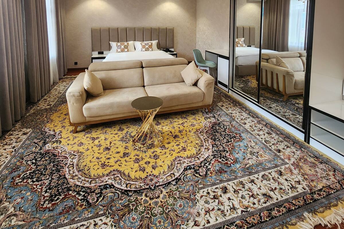 A spacious bedroom with a large bed, a sofa, a small table, and a large mirror.