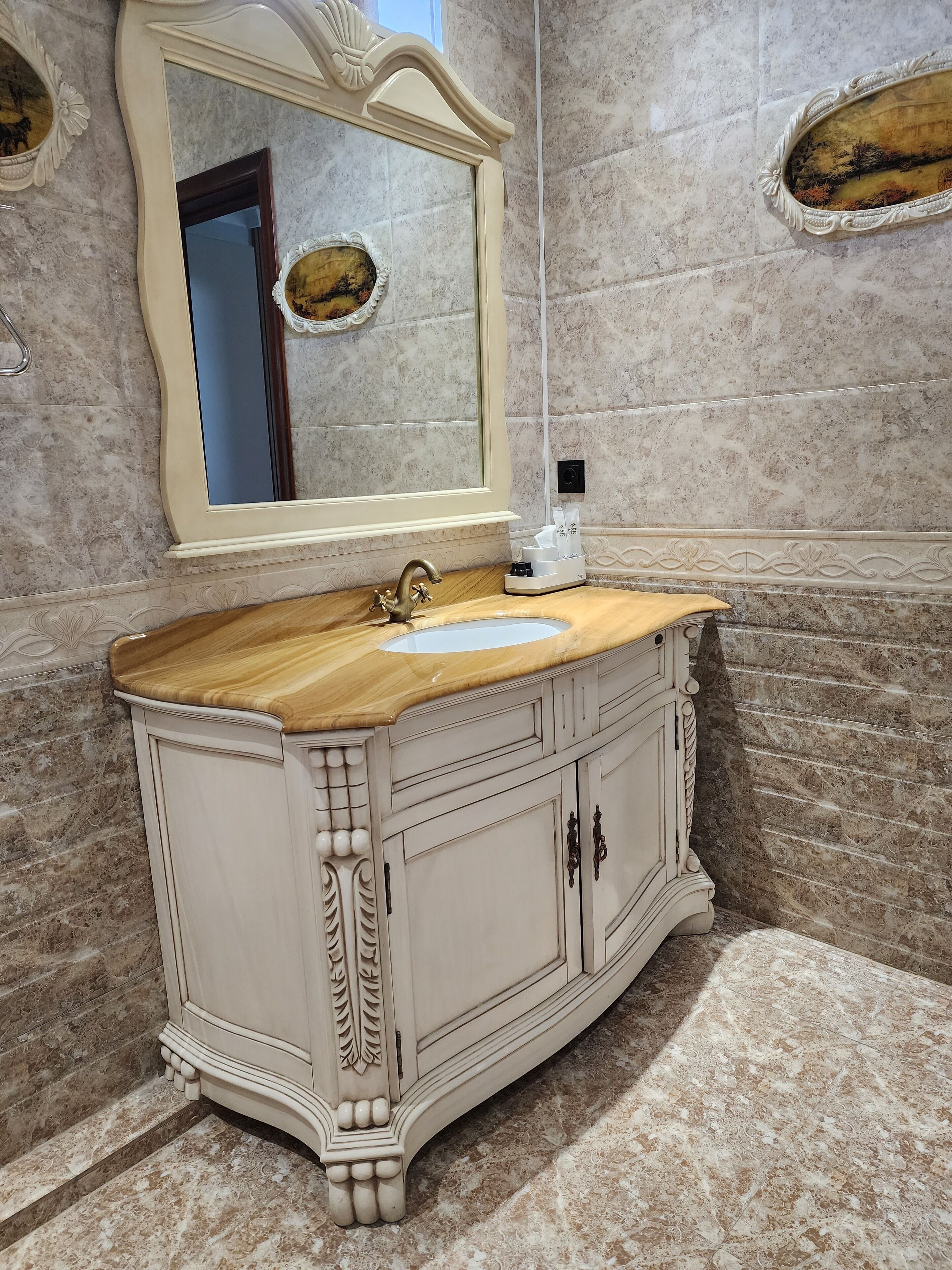 A bathroom with a marble sink, a large mirror, and a decorative cabinet.