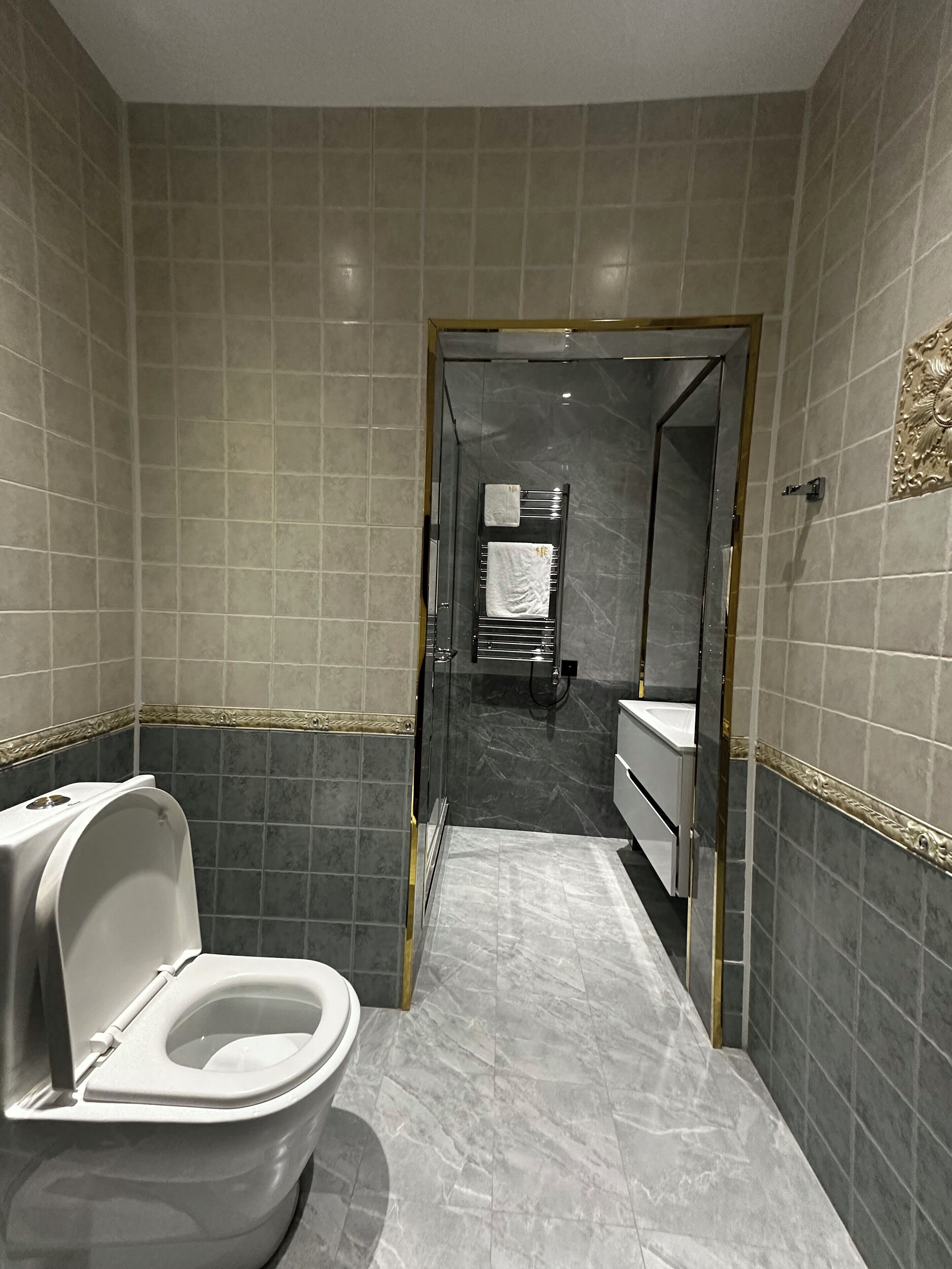 Une salle de bain moderne équipée de toilettes, d’un lavabo et d’un espace douche.