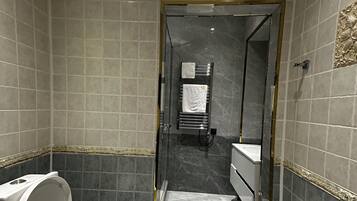 Une salle de bain moderne équipée de toilettes, d’un lavabo et d’un espace douche.