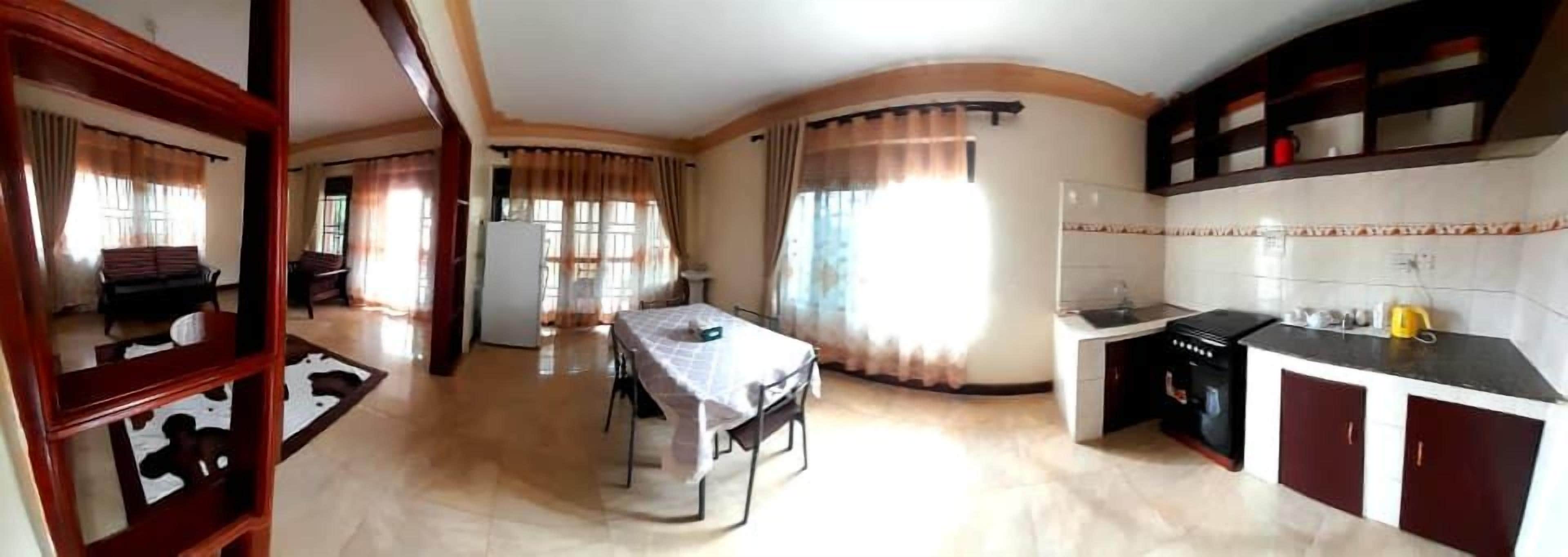 A spacious living area with a dining table, kitchen, and a large window providing natural light.