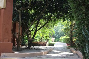 A pathway lined with trees and a bench, leading to a building with a red exterior.