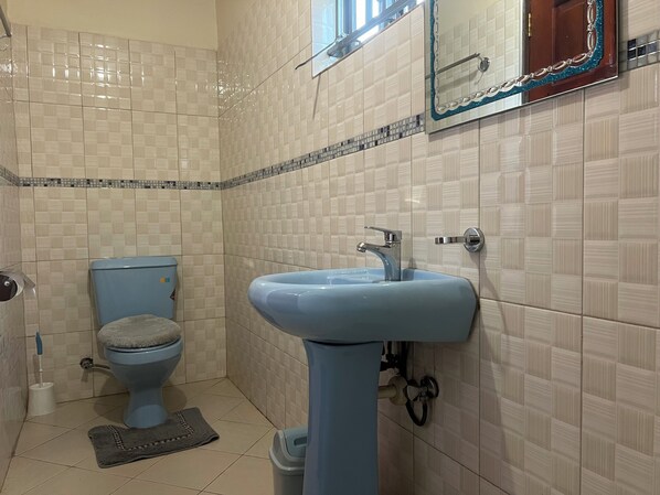 A bathroom with a toilet, sink, and tiled walls.