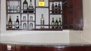A bar area with shelves of various liquor bottles and glasses. - Montane Safaris Hotel (Fort Portal)