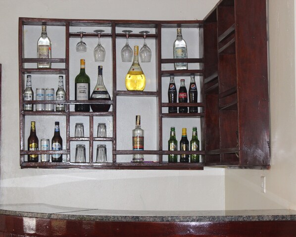 Zona de bar con estantes llenos de botellas de licores y vasos.