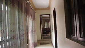 A hallway with a staircase leading to a dining area, featuring a patterned curtain and a wooden door. - Montane Safaris Hotel (Fort Portal)