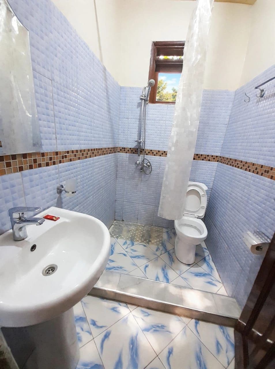 A bathroom with a white sink, a toilet, and a shower area.