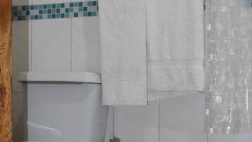 A bathroom with a toilet, a towel rack with a white towel, and a shower curtain.