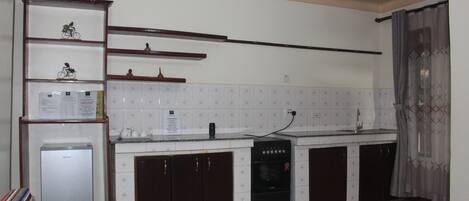 A compact kitchen with a refrigerator, stove, and cabinets.