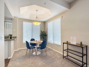 A dining area with a round table, blue chairs, a hanging light fixture, and a small console table with a plant. - TWO CozySuites at Kierland Commons  (Scottsdale)