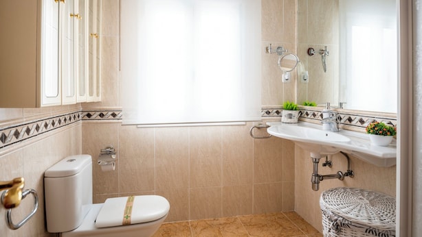 A bathroom with a toilet, sink, and mirror. - Centro y Confort by Wehomes (Santander)