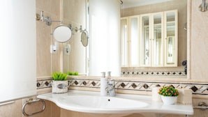 A bathroom with a white sink, two mirrors, a towel dispenser, and a potted plant. - Centro y Confort by Wehomes (Santander)