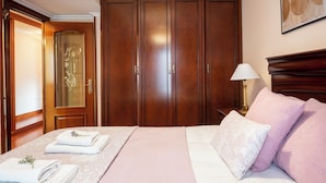 A hotel room with a large wardrobe, a bed with pink bedding, and a bedside table with a lamp. - Centro y Confort by Wehomes (Santander)