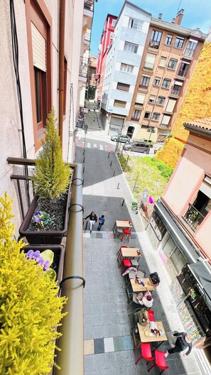 Een terras met tafels en stoelen, omgeven door gebouwen met balkons en ramen.