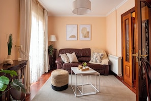 Een gezellige woonkamer met een bruine leren bank, een witte salontafel en een houten bijzettafeltje met een lamp.