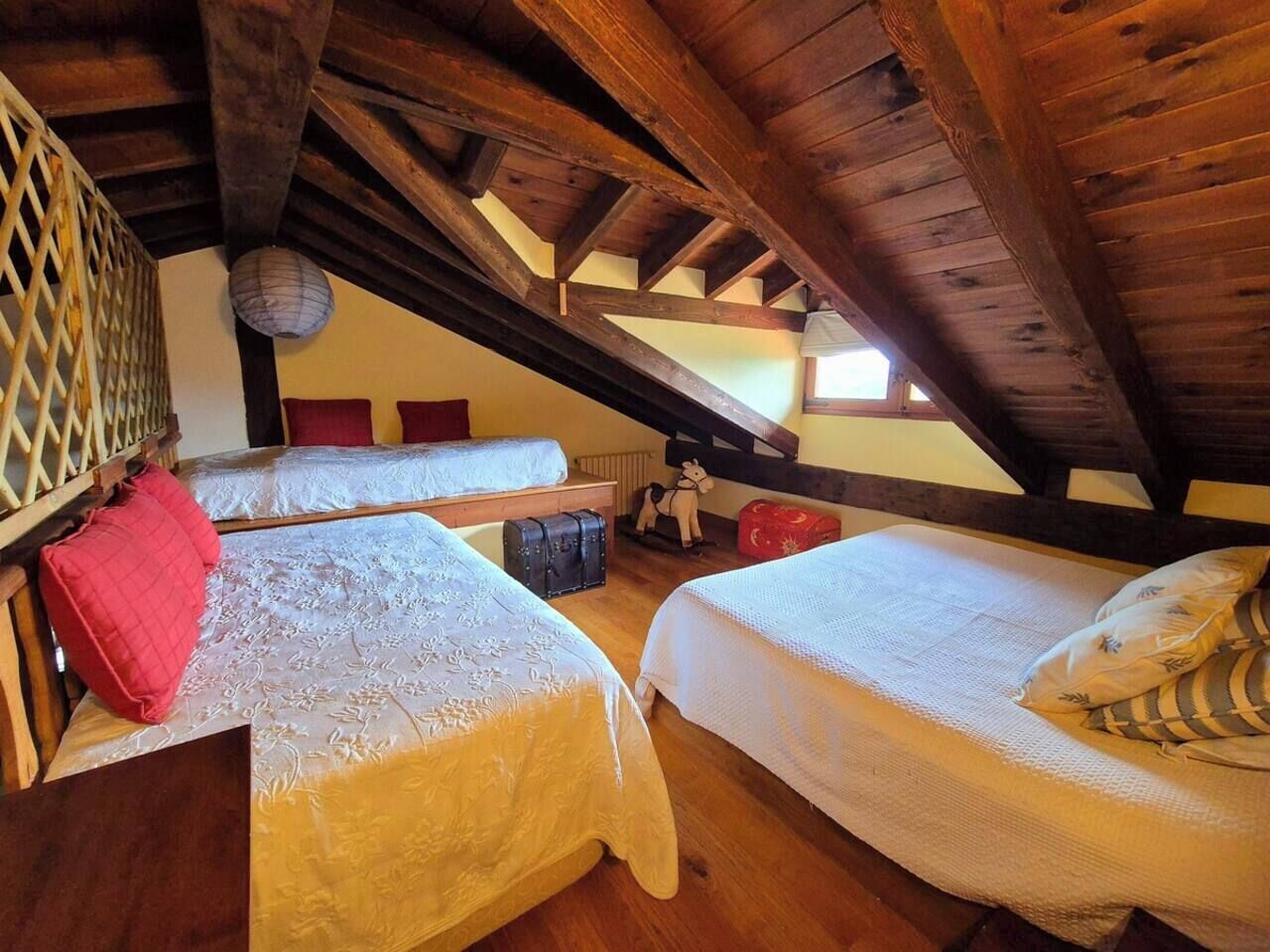 Een kamer met twee bedden, houten balken, een sprietwerk muur en een hanglamp.