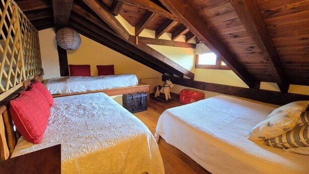Una habitación con dos camas, vigas de madera, un muro con celosía y una lámpara colgante.
