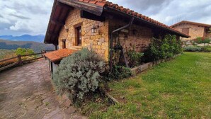 Una casa de piedra con techo de tejas, un sendero de piedras y un área con césped.