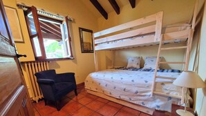 Una habitación con literas, un escritorio, una silla, una lámpara y un radiador.