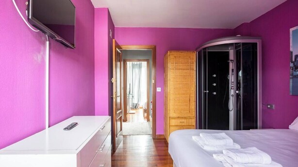 Habitació d'hotel amb llit, armari, escriptori i televisió.