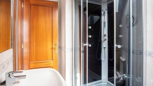 Un baño con ducha de vidrio, puerta de madera y bañera blanca.