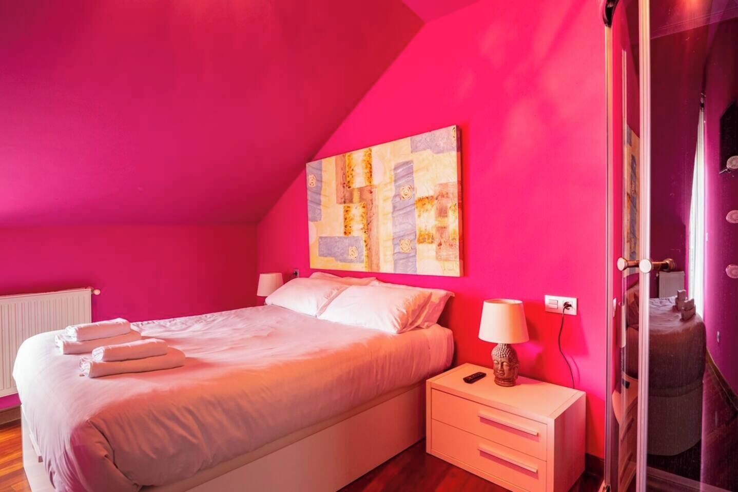 Un dormitorio con cama, mesitas de noche y un cuadro en la pared.