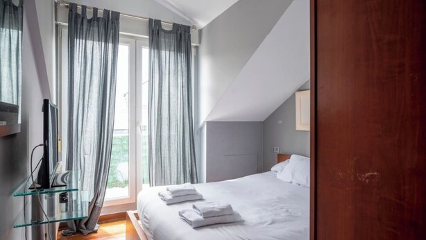 Un dormitorio con cama, una mesita de vidrio y cortinas.