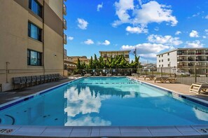 Ein Swimmingpool mit Liegestühlen und einem Zaun, umgeben von Gebäuden.